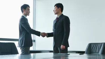 Two people shaking hands in a conference room