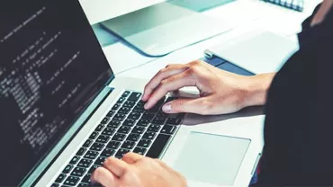 Person coding on a laptop at a desk.