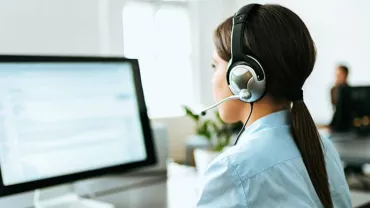 Person wearing a headset working at a computer.