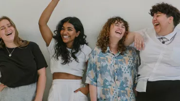 Four people standing together, smiling in front of a white background.