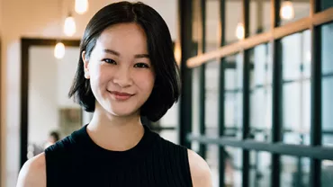 Person smiling in a modern office setting with glass partitions.