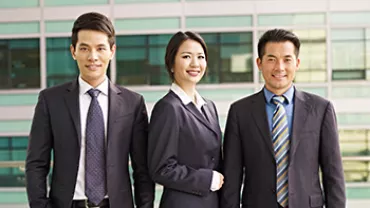 Three professionals in suits standing in front of an office building