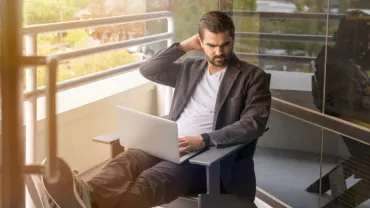 A person working on a laptop on a balcony.