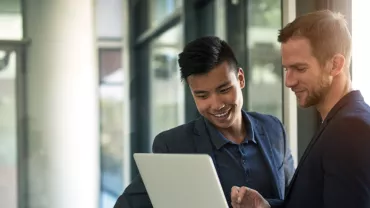 Two people looking at a laptop in an office