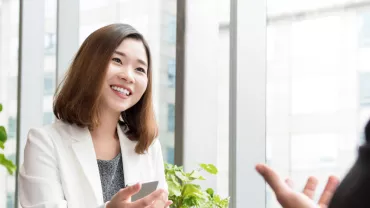 Person smiling during a meeting in a bright office.