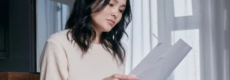 A person reviewing papers with light coming through curtains.