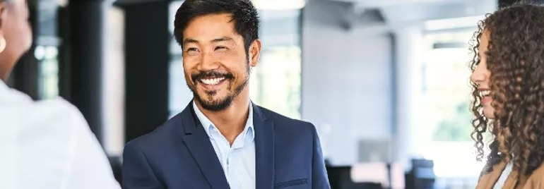 Person in suit smiling and shaking hands in an office setting.