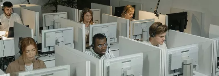 People working at individual cubicles with computers.